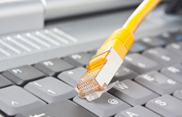 Gelbes Netzwerkkabel liegt auf einer Computertastatur, Symbolbild für moderne Netzwerktechnik und Datenanbindung.